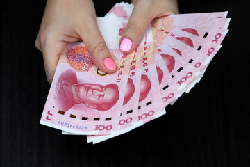 Chinese yuan banknotes in female hands. Woman counting paper money