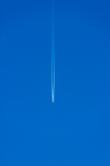 a wake of an airplane in the  background of a blue sky