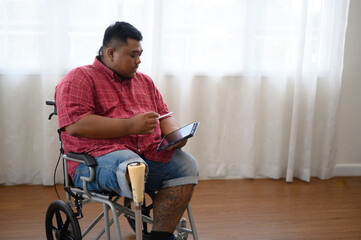 A big fat man sits on a wheelchair and uses a tablet.