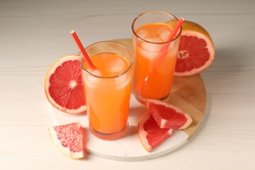 Tasty freshly made grapefruit juice and fruits on white wooden table