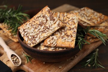 Cereal crackers with flax, sunflower, sesame seeds and rosemary on table, closeup