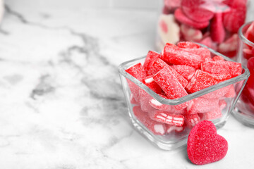 Different yummy candies in glass bowls on white marble table, closeup. Space for text