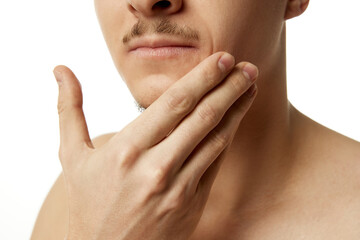 Cropped photo of young man touching his trimmed beard, chin against white studio background. Close-up. Concept of beauty procedures, male health, body care, spa treatment, hygiene.