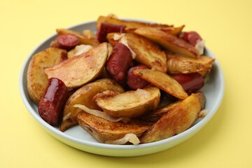 Delicious baked potato with thin dry smoked sausages and onion on yellow table, closeup