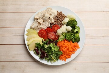 Balanced diet and healthy foods. Plate with different delicious products on light wooden table, top view