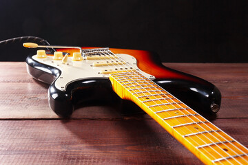 Solid body electric jazz guitar closeup on wooden background. Selective focus.
