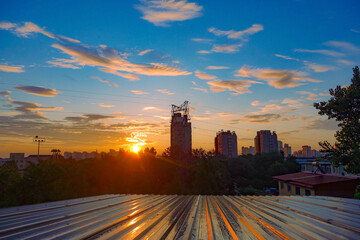 A high-voltage power tower and urban skyline set against the backdrop of a brilliant morning sunrise and sunset