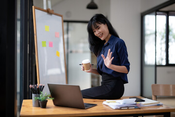 Concentrated businesswoman working using laptop in modern office with coffee cup in her hand.