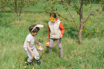 Easter egg hunt. Two children hunt for Easter eggs in a spring garden. Easter tradition. Laughing children in garden with basket spring
