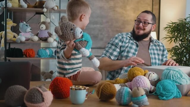 Dad and son play with a teddy bear in the family workshop at home