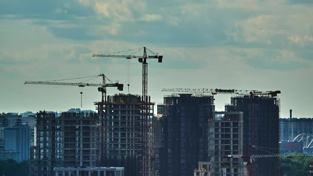 Hyperlapse real estate construction multistory buildings cranes move clouds glides at sky City development real estate construction. Cityscape transforms with new buildings real estate construction.