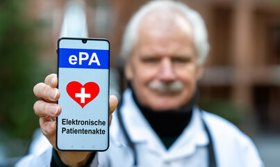 A doctor is holding a mobile phone with the text 'ePA elektrosche Patientenakte' (electronic health...