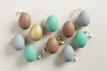 Pastel Easter Eggs as minimal pattern with white blooming Flowers on beige color, top view colorful chicken egg. Easter celebration concept. Festive food, still life holiday, aesthetic flat lay