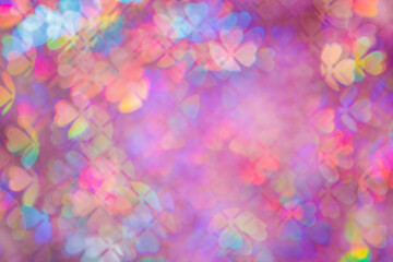 Defocused abstract floral bokeh background purple color, flare from lights, blurred bokeh of clover leaves shape as holiday texture. Colorful festive aesthetic textured lighting pattern