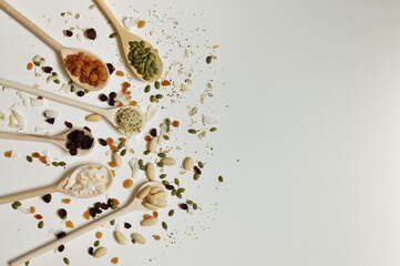 Organic seeds and spices on wooden spoons on white background
