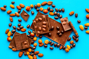Different variety of chocolate and hazelnut on blue background top view