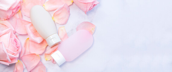 Bottles of cosmetics lie on rose petals