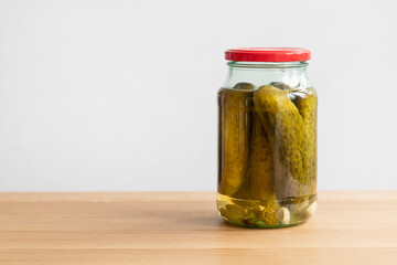 A jar of pickles standing on a wooden table