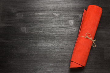 Red leather rolled up pieces scroll on the black table background. Top view.