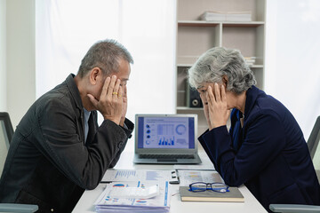 Two senior Asian businessmen, male and female, are stressed out with paperwork and are tired, have...