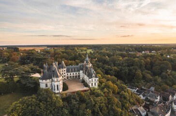 A stunning aerial view showcases a grand castle nestled within a sea of verdant trees, offering a...
