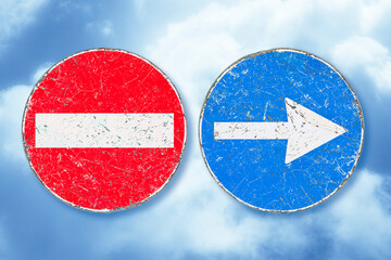 Directional arrow road sign and no entry road sign against a sky background - concept image
