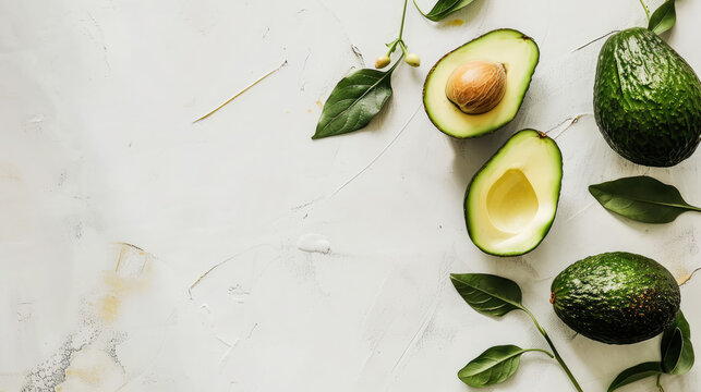Halved avocados with pits neatly arranged around the edges of a white background, creating a natural frame.