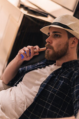 Young smoker vaping on the couch at home. Lifestyle concept