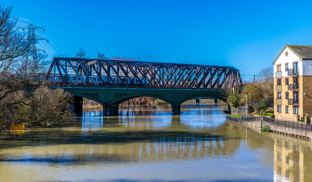 A close up view of a train on the historic cast iron railway bridge over the River Nene in Peterborough, UK on a bright sunny day