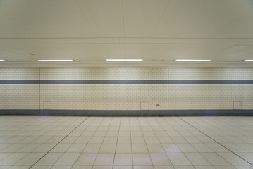 A bland tiled subway lit by strip lighting