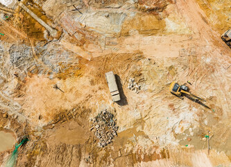 Excavator on earthmoving with grab crane unloads sand from freight car,aerial view.