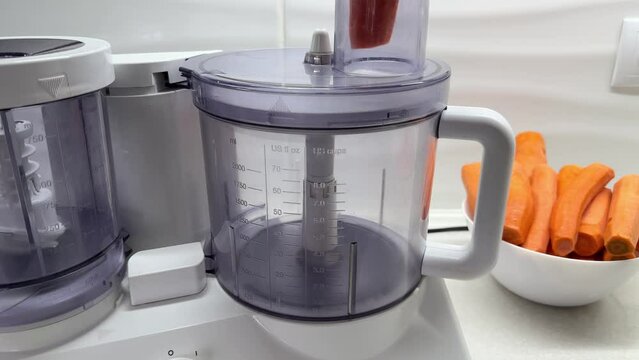 Process of chopping carrots in an electric food processor. Sliced or grated vegetables, grinding fresh  root vegetable, home cooking, close up, 4k
