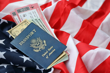 Blue United States of America passport with money and airline tickets on US flag background close up. Tourism and travel concept