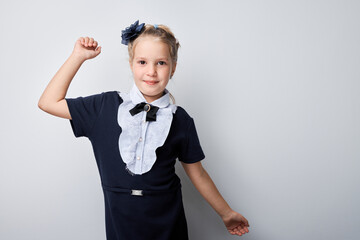 Confident young girl posing with raised fist wearing school uniform and blue headband