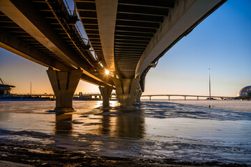 View from under the Western high-speed Diameter highway connecting the Northern part of St. Petersburg and Krestovsky Island, panorama in winter with ice on the river at sunset