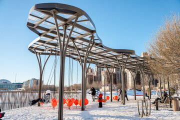 A playground with swings under a canopy in the courtyard of a multi-storey building in winter. Saint Petersburg, Russia - 10 Feb 2024