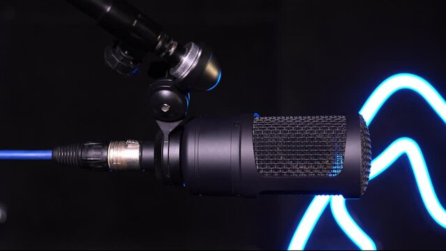 Studio condenser microphone isolated in black, studio microphone and pop screen on microphone in empty recording studio with copy space, in neon blue light. vertical video