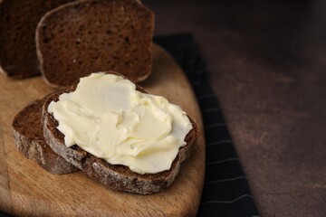 Slices of tasty bread with butter on grey textured table, closeup. Space for text