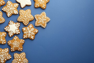 Fototapeta na wymiar Tasty star shaped Christmas cookies with icing on blue background, flat lay. Space for text