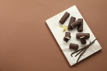 Glazed curd cheese bars, vanilla pods and flower on light brown background, top view. Space for text