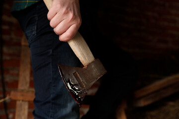 Man holding bloody axe indoors, closeup view