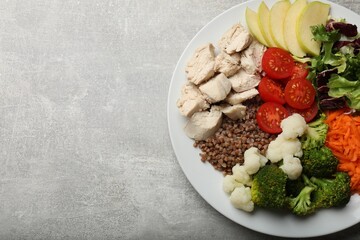 Balanced diet and healthy foods. Plate with different delicious products on grey table, top view. Space for text