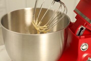 Modern red stand mixer with cream indoors, closeup