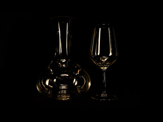 A wine pourer and wine cup in transparent crystal in a dark room and black background    