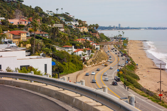 Santa monica mountiains, filled with mansions, meeting the ocean. Looking North up the Pacific Coast Highway towards Pacific Palisades on a hazy day.