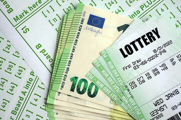 Green lottery tickets and euro money bills on blank with numbers for playing lottery close up