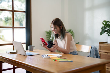 Creative designer woman checking photo on smartphone and working graphic design in home studio