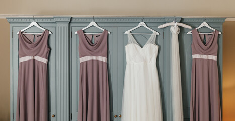Wedding and bridesmaid dresses hanging on blue dresser