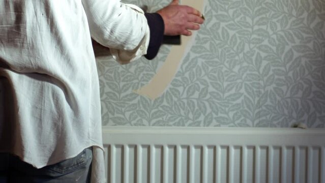 Hand stripping wallpaper from home internal wall close up