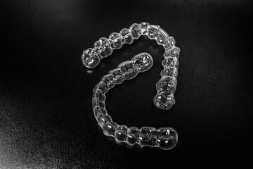 Invisible dental teeth brackets tooth aligners on black background. Plastic braces dentistry...